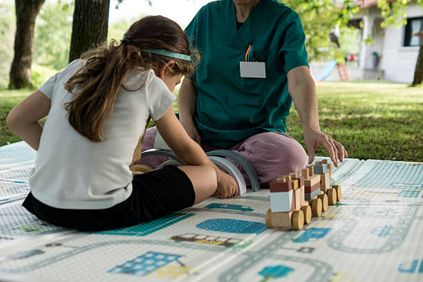 Close-up of a therapeutic interaction where the professional guides the child’s movement to build a wooden structure, promoting social and motor skills.