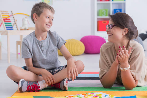 Happy little child during during therapy with school counselor, learning and having fun together sitting on the floor in a colorful playroom
